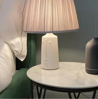 close up of a bedside table with a lamp and green bed