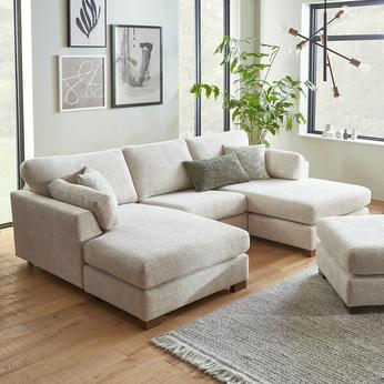 Light grey u shaped corner sofa in a bright living space with green scatter cushions