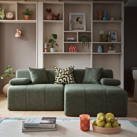 green compressed sofa with shelving unit on back wall