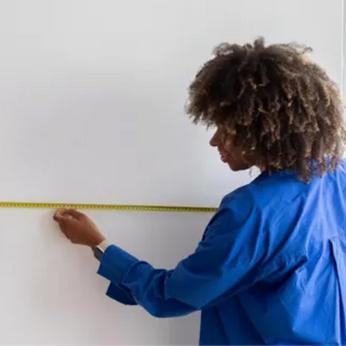 lady measuring a wall with tape measure