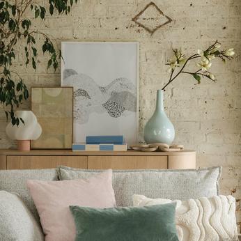 close up of cream sofa and multi scatters with sideboard behind
