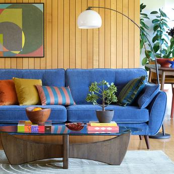 Blue sofa with retro styling and panelled wall behind