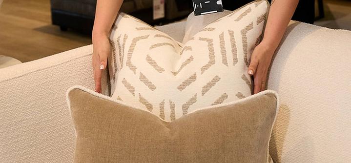 hands shown to be plumping up sofa scatter cushions 