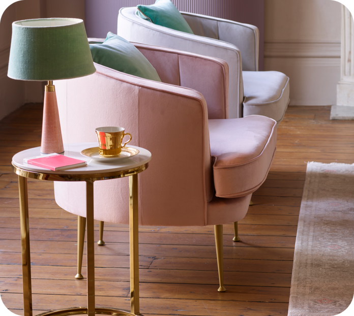 pale and purple velvet accent chairs with gold legs next to a pink and green lamp