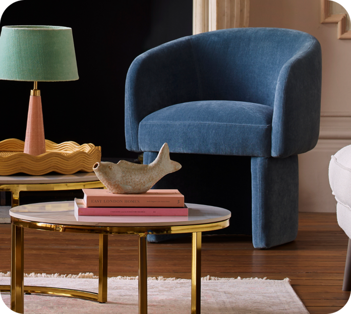 blue accent chair next to a marble next table with gold legs