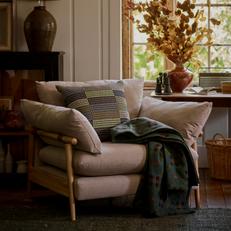 French Connection Hoxton chair with wooden bamboo style frame finished with green scatters and a throw