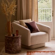 French Connection Molten swivel chair with a purple scatter cushions next to an olive tree in a cosy living space with orange rug
