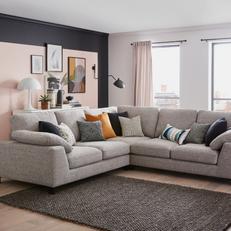 Light grey corner sofa with a mixture of scatter cushions in monochrome and orange