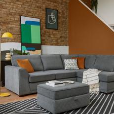 Dark grey corner sofa with orange and monochrome scatter cushions