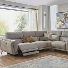 Light grey recliner corner sofa next to a large window