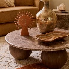 brown marble round coffee table with circular ball feet on a orange patterned rug 