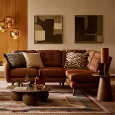 Brown leather corner sofa with brown patterned canvases and patterned scatter cushions with brown curved coffee table