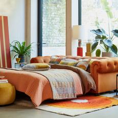 orange belair sofa bed next to a large window