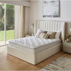 Cream velvet bed next to neutral wall with a mattress
