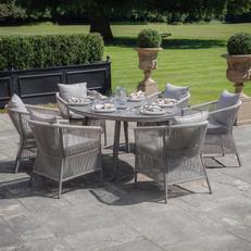 Light grey round garden furniture with rattan dining chars in a garden