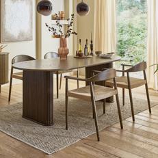 Oval walnut dining table with fluted legs and a dark marble top with wooden ratten dining chairs