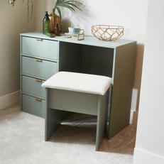 Sage green chest of drawers with gold handle and a cushioned stool