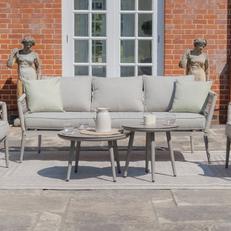 Light grey garden sofa with nest table outside a sunny garden