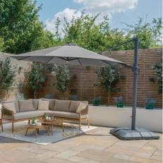 Large grey cantilever parasol sitting over a wooden garden set in a sunny garden