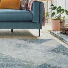 BLue patterned rug next to a blue fabric sofa