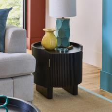 Round black side table next to a grey sofa 