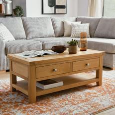Oak tv stand ona orange patterned rug next to a light grey sofa