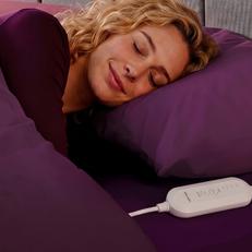 A women with blonde hair fast asleep under purple bedding with a heated blanket