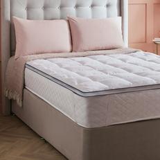 Beige buttoned divan bed with mattress topper and two pillows