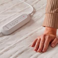 Close up of a hand touching a Silentnight heated blanket