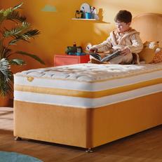 A young boy lay upon a orange single divan bed with a Silentnight mattress with orange