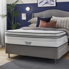 Light grey divan bed next to a navy blue wall with a Silentnight mattress wiht blue and pink pillows
