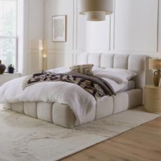 fluffy white boucle cloud like bed in a bright and neutral bedroom with monochrome throw and a fluffy rug