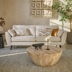 white boucle mid century sofa with wooden legs next to a neutral wall with a round wooden coffee table