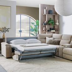 White corner leather sofa on a white fluffy rug with a sofa bed set up with white bedding