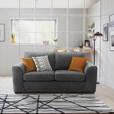 Small 2 seater grey sofa with orange and monochrome scatter cushions next to a monochrome rug