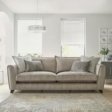 Light beige fabric sofa with silver trim on the arms next to a fluffy beige rug