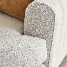 Close up of a white boucle fabric on a sofa with orange scatter