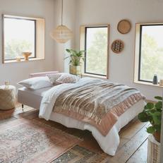 pink sofa bed with patterned pastel pink bedding on a wooden floor 