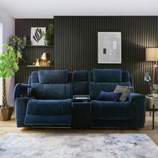 Dark blue sofa next to a black wall with a light patterned fluffy rug