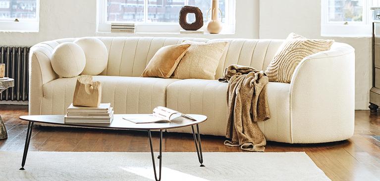 70s style cream curved sofa with fluted back in a large bright living space with neutral scattered and a throw