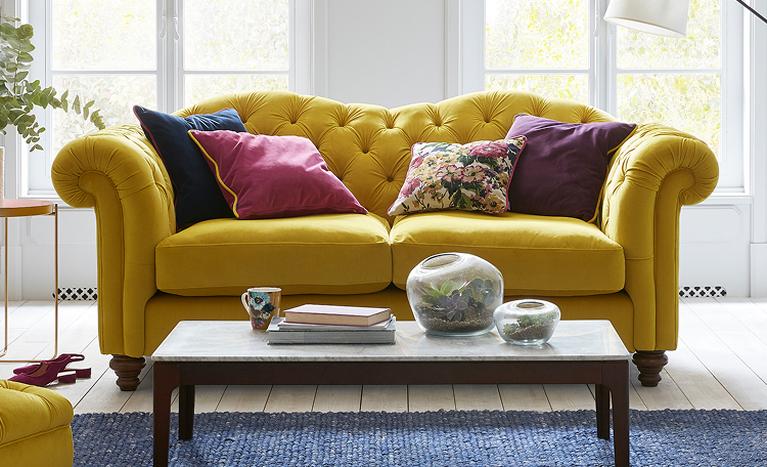 Joules yellow chesterfield sofa with colourful patterned scatters