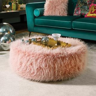 Pink furry footstool next to a green velvet sofa