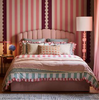 pink bed against a pink stripy wall in a colourful pink bedroom