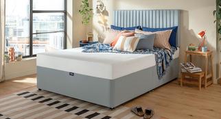 Silentnight Rolled mattress on a pale blue divan bed with colourful scatters