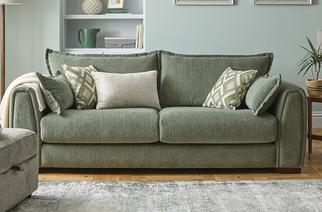 Sage green fabric sofa with green patterned scatter cushions next to a green paterrned rug