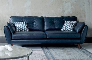 Dark blue leather mid century style sofa with blue and white patterned scatters on a blue patterned rug