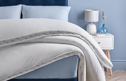 Close up of a duvet set on a bed with a white bedside table