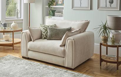 Cream fabric cuddle sofa with sage green scatter cushions and a sage green rug