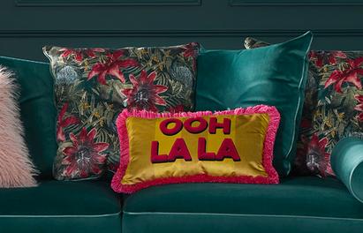Velvet teal sofa with  matching scatter cushion and a floral scatter with pink and gold scatter saying ooh la la