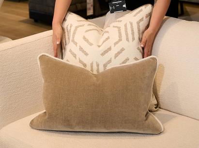 Close up of a women plumping a brown and brown patterned scatter cushions